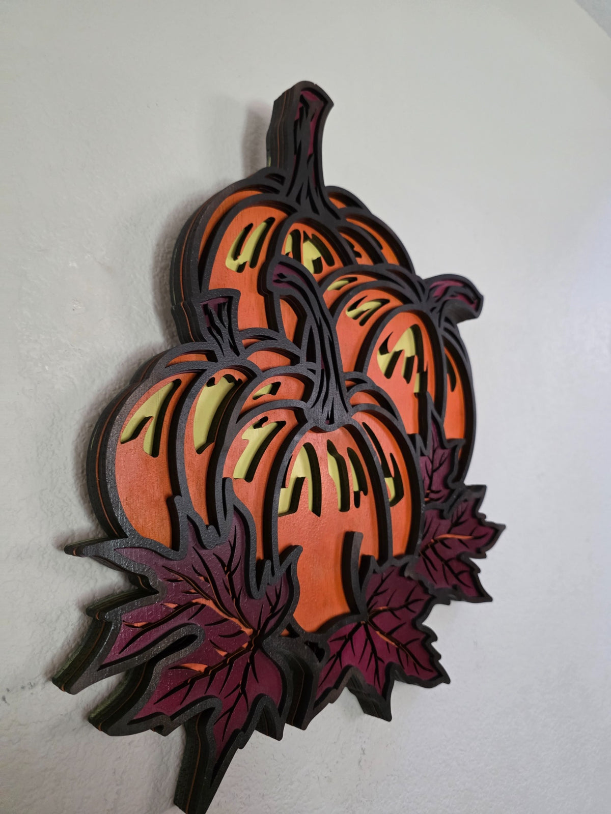 Angled side view of layered wooden pumpkin and maple leaves wall art showing dimensional wood layers