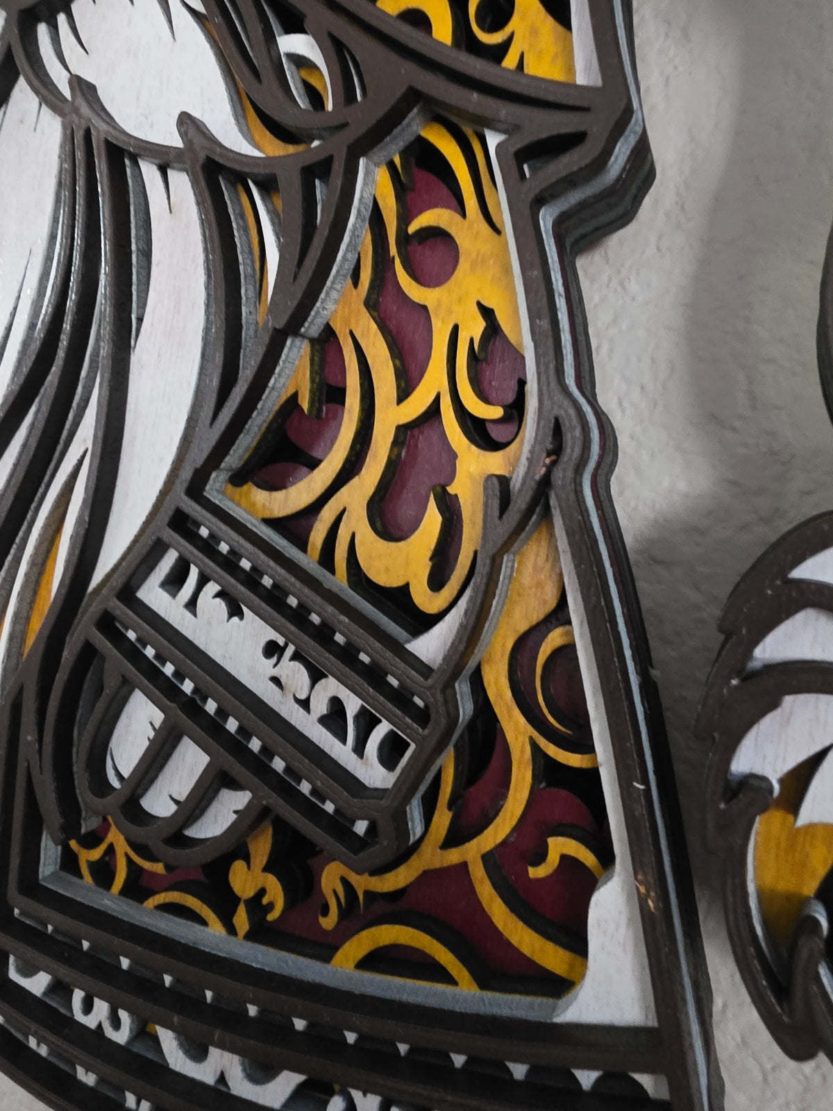 Close-up detail of ornate red and gold layered wood pattern on Christmas gnome wall art