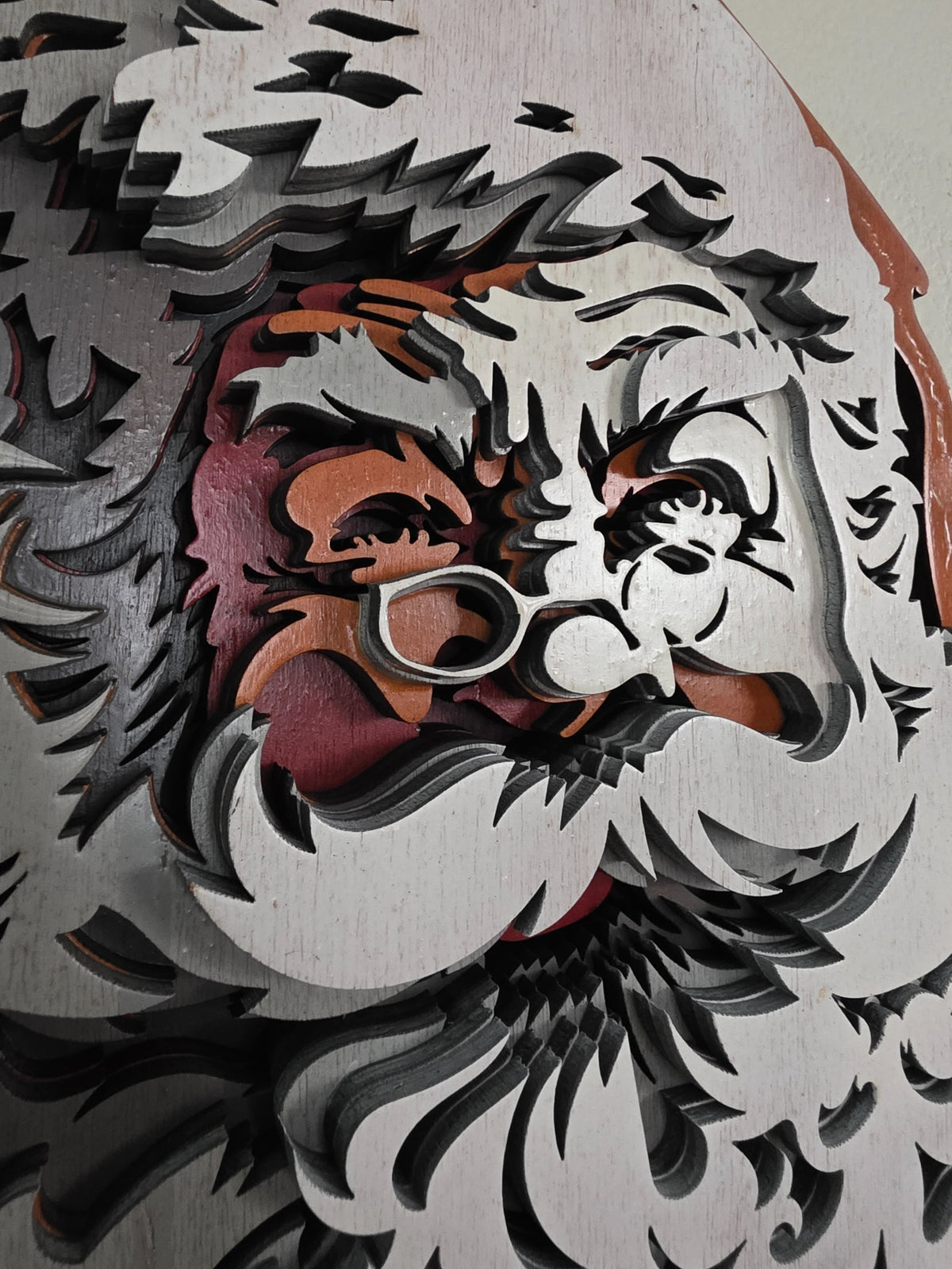 Close-up detail of Santa Claus face, glasses, mustache, and layered wood craftsmanship
