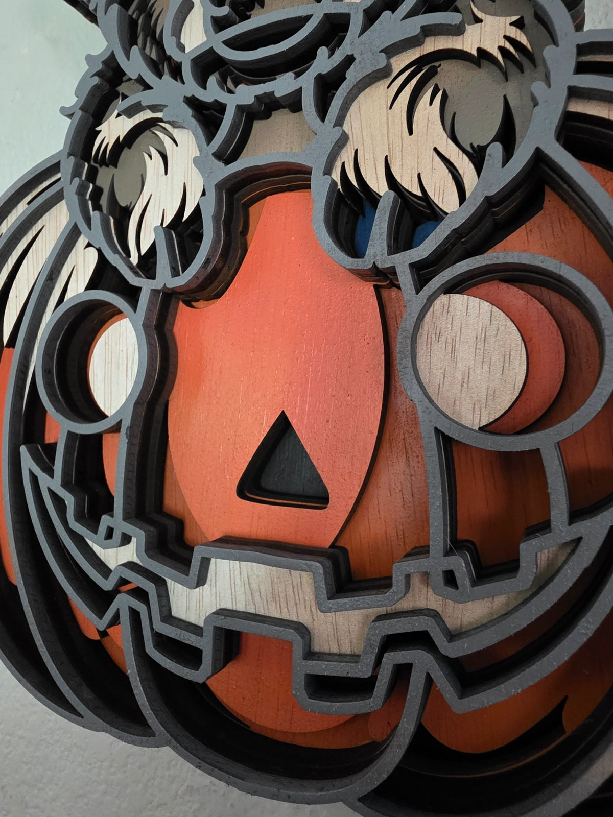 Close-up detail of jack-o-lantern pumpkin on layered wooden Highland cow Halloween wall art