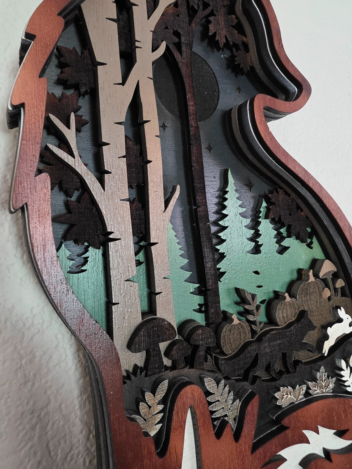 Close-up detail of birch trees, moon, pine forest, and layered wood depth inside fox silhouette