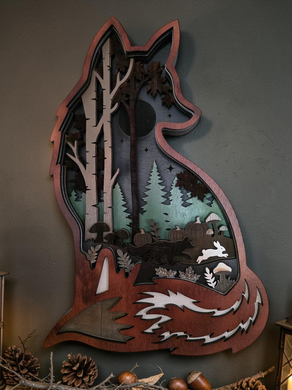 Layered wooden fox forest wall art styled with pinecones, acorns, lantern light, and cozy fall decor