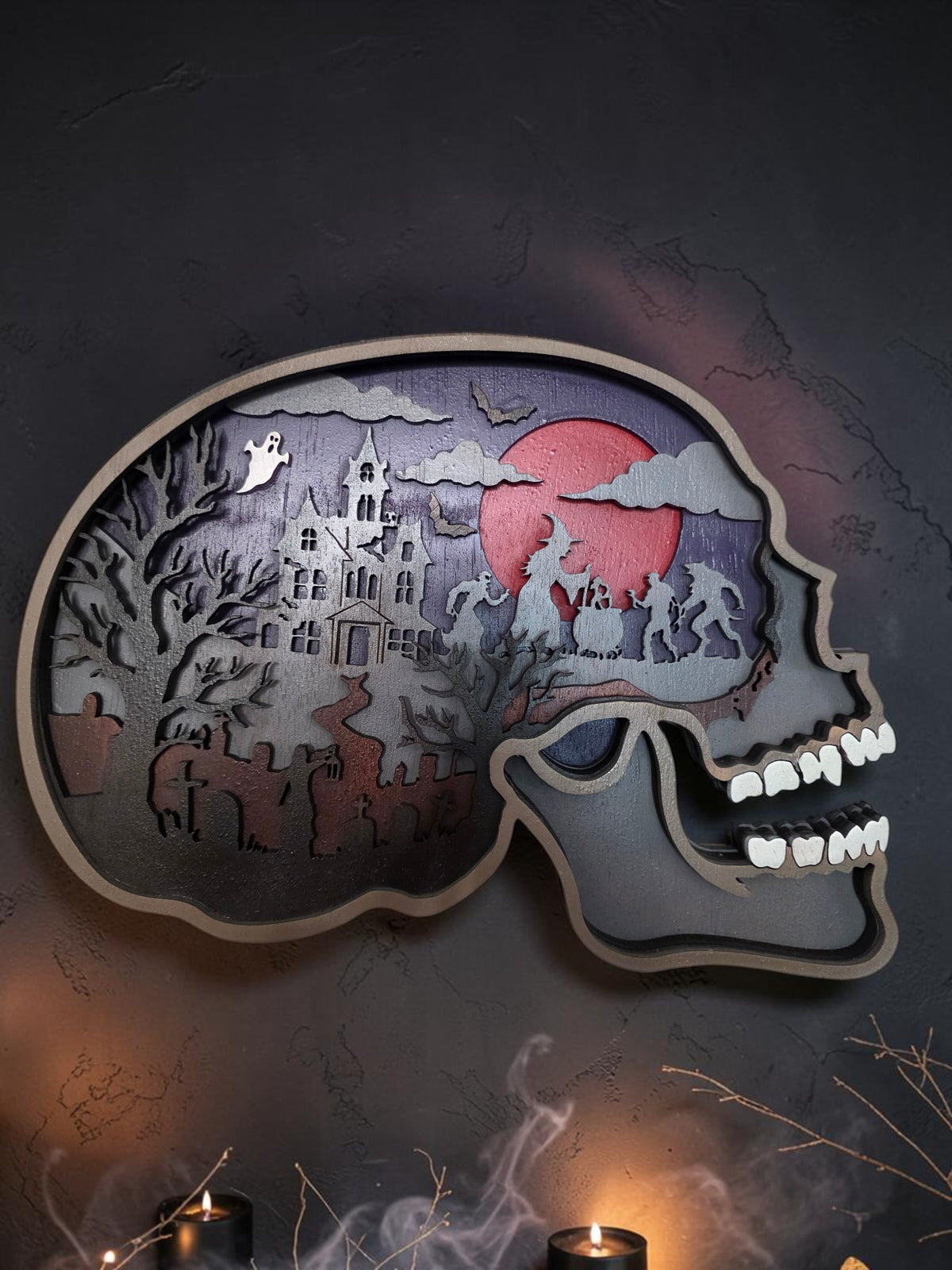 Layered wooden skull Halloween wall art with haunted house, cemetery, ghosts, bats, and red moon