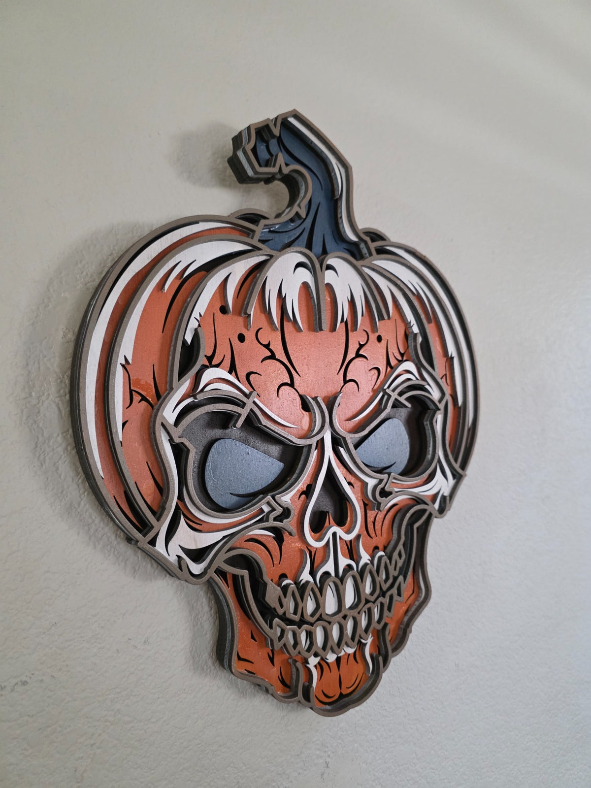 Angled side view of layered wooden pumpkin skull Halloween wall art showing dimensional stacked wood layers